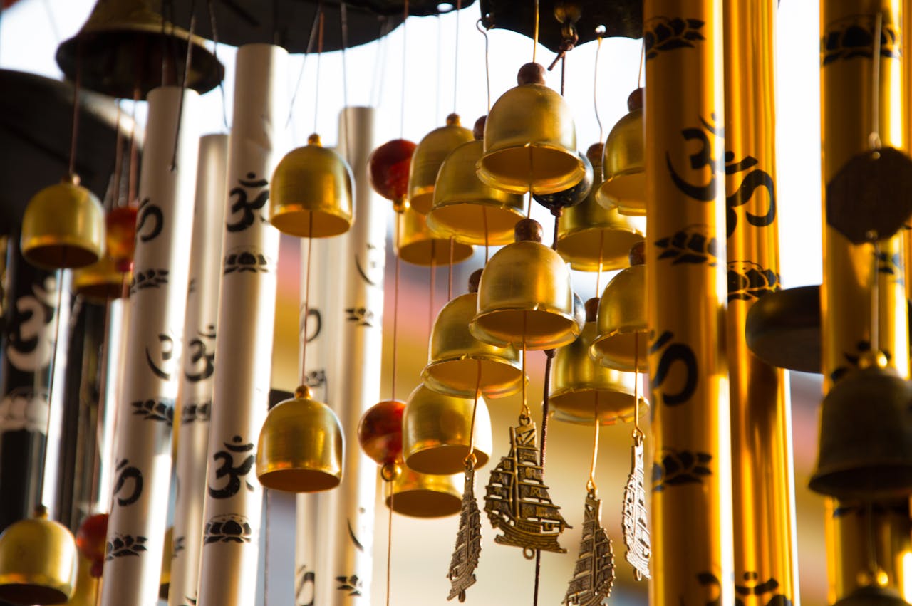 our-story Close-up of intricately designed golden wind chimes featuring Om symbols, creating a serene ambiance.